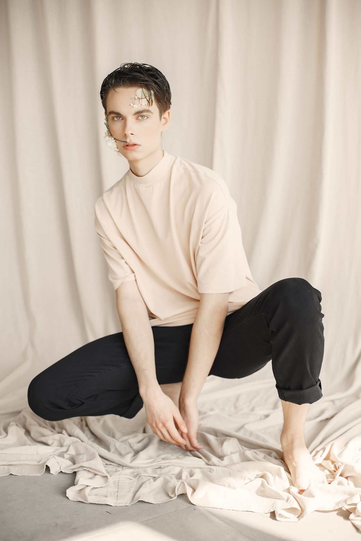 Hombre con polera crema y pantalón negro en estudio