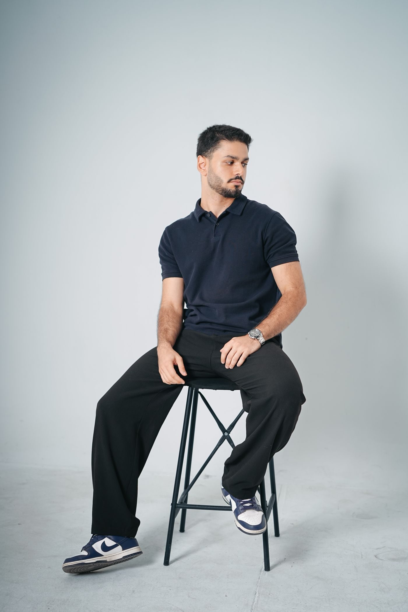 Hombre con polera polo azul marino sentado en un piso